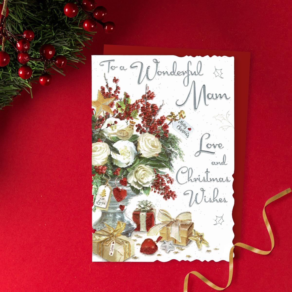 To A Wonderful Mam Love And Christmas Wishes Featuring A Vase Of White Roses And Red Berries Plus Gifts. Finished With Silver Foiled Lettering, Red Glitter Detail And Red Envelope