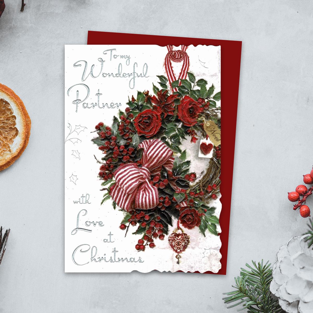 To My Wonderful Partner With Love At Christmas Featuring A Beautiful Festive Wreath Of Red Roses, Berries And Large Bow. Finished With Silver Foiled Lettering, Red Glitter Detail And Red Envelope