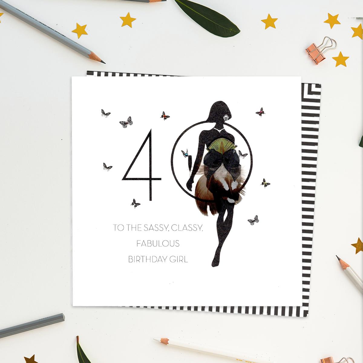 A stunning, luxury, handcrafted card with gem embellishments and feathers from Five Dollar Shake. Showing A Woman In Black Silhouette Standing In Front Of The Number 40. Caption: 'To The Sassy, Classy, Fabulous Birthday Girl'. Blank Inside For Your Own Message. Complete With White Envelope With Black and White Striped Border.