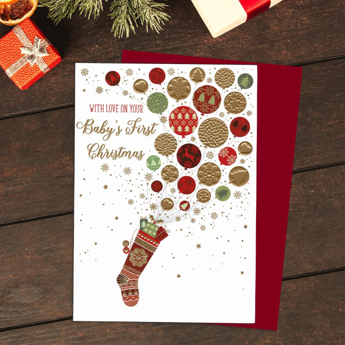 With Love On Baby's First Christmas Card Showing A Christmas Stocking Filled With Balloons. Finished With Gold Foil Lettering And Accents. Completed With a Red Envelope