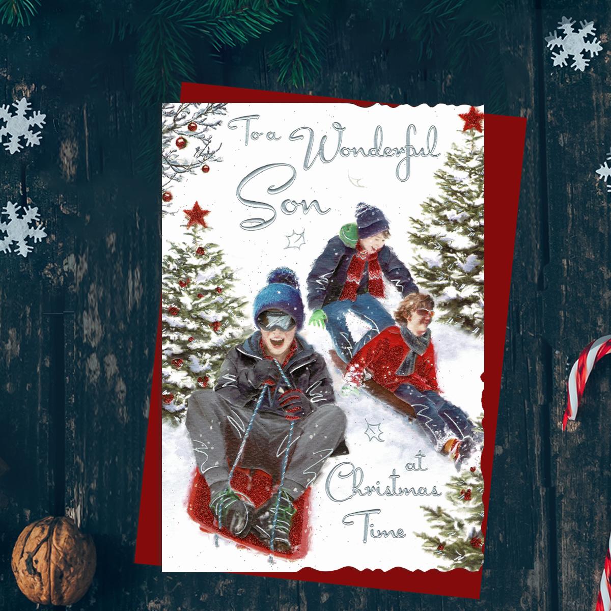 To A Wonderful Son At Christmas Time Featuring Three Boys On Sledges In The Snow. Finished With Silver Foil lettering, Red Glitter And Red Envelope