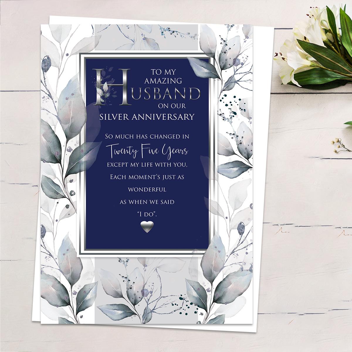 'To My Amazing Husband On Our Silver Anniversary' Card Showing A Border Of Leaves Around A Navy Rectangle With Gold Foiled Edge. Heartfelt Words And White Envelope