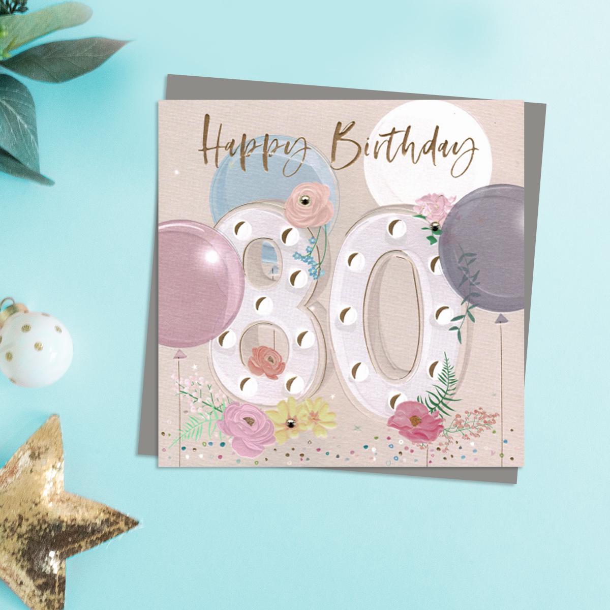 Happy 80th Birthday Design Featuring Embellished Flowers And Balloons. Completed With Gold Foil lettering And A Co-Ordinating Grey Envelope