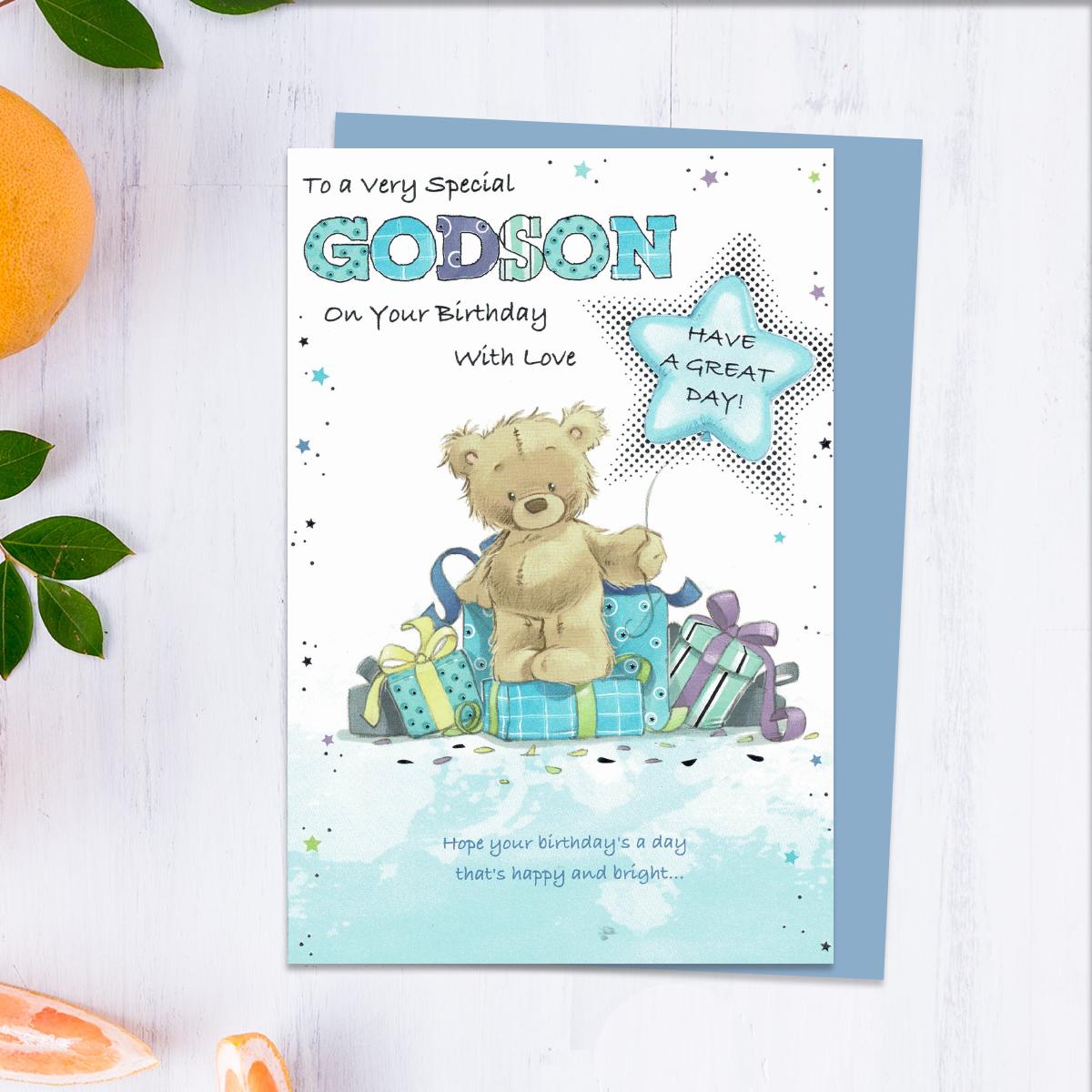 To A Very Special Godson On Your Birthday With Love Card Featuring A Cute Teddy On A Stack of Gifts. With Added Silver Foiled Detail And White Envelope