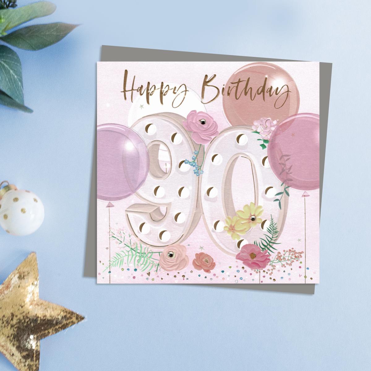 Happy 90th Birthday Flowers And Balloons Design With Embellishments. This Stunning Card Is Completed With Gold Foil lettering And A Co-Ordinating Grey EnvelopeWith