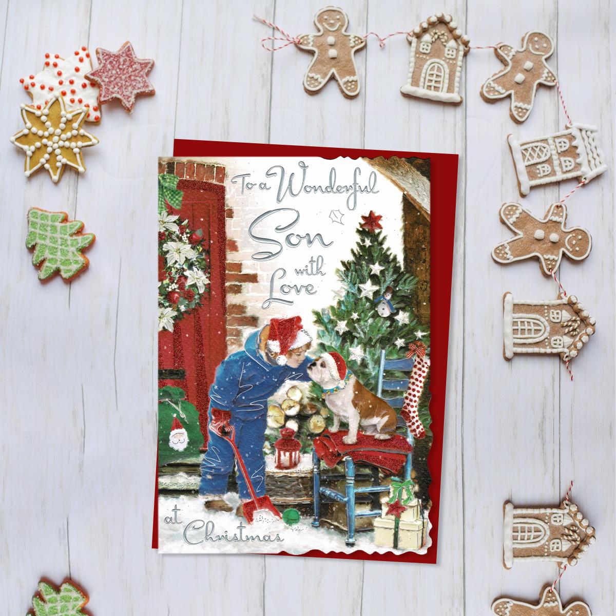 To A Wonderful Son With Love Featuring A Boy With His Dog In The Snow! Finished With Silver Foiled Lettering, Red Glitter Detail And Red Envelope