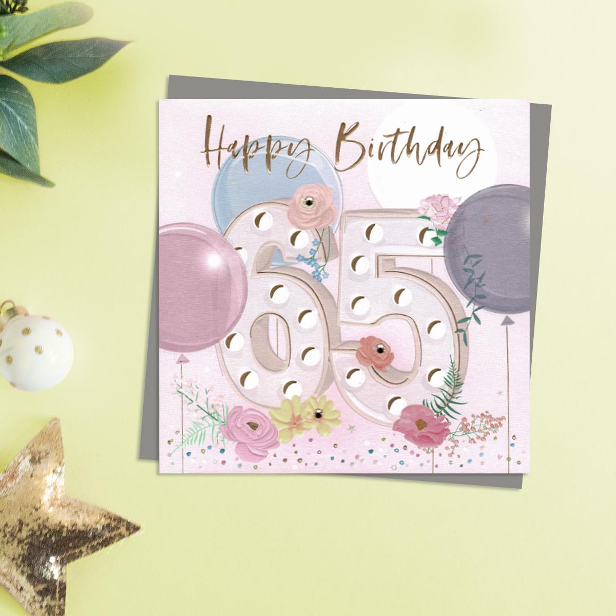 Happy 65th Birthday Design Featuring Embellished Flowers and Balloons. Completed With Gold Foil Lettering and A Co-Ordinating Envelope