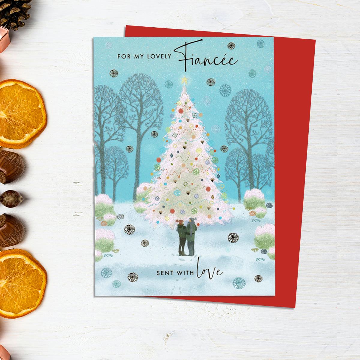 For My Lovely Fiancée Christmas card Showing A Beautiful White Sparkling Christmas Tree With a Couple Beside It. Finished With Gold Lettering And A Red Envelope