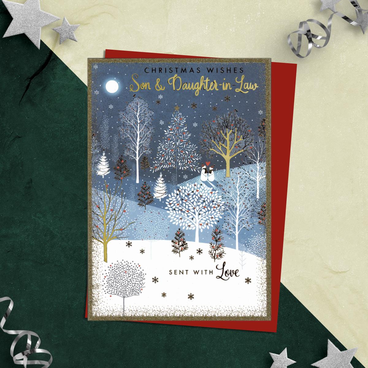Christmas Wishes Son & Daughter In Law Sent With Love Featuring A Snowy Forest Scene Enhanced With Gol Foil Trees And Glitter. Two Snowmen With A Red Heart Above Them Complete This Design. finished With Red Envelope, Printed Insert And Verse