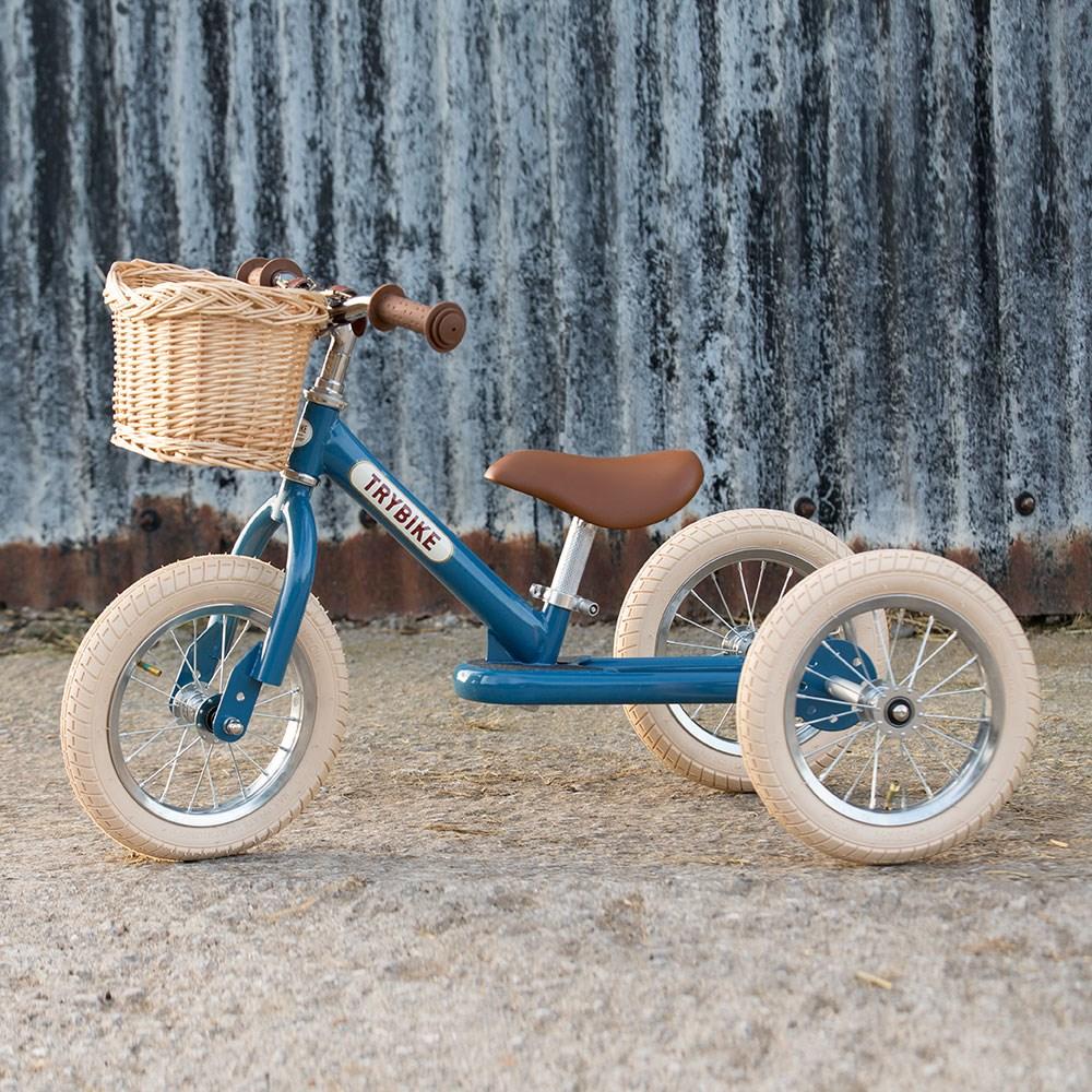 Wicker basket on the front of a blue Trybike with corrugated iron in the background.