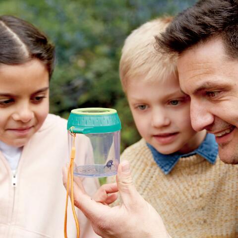 Man with 2 children outdoors looking at the bug they've caught in the Bug Jar