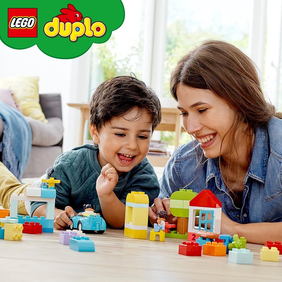 Young boy and woman, both with dark hair playing with Duplo pieces that are in the foreground.