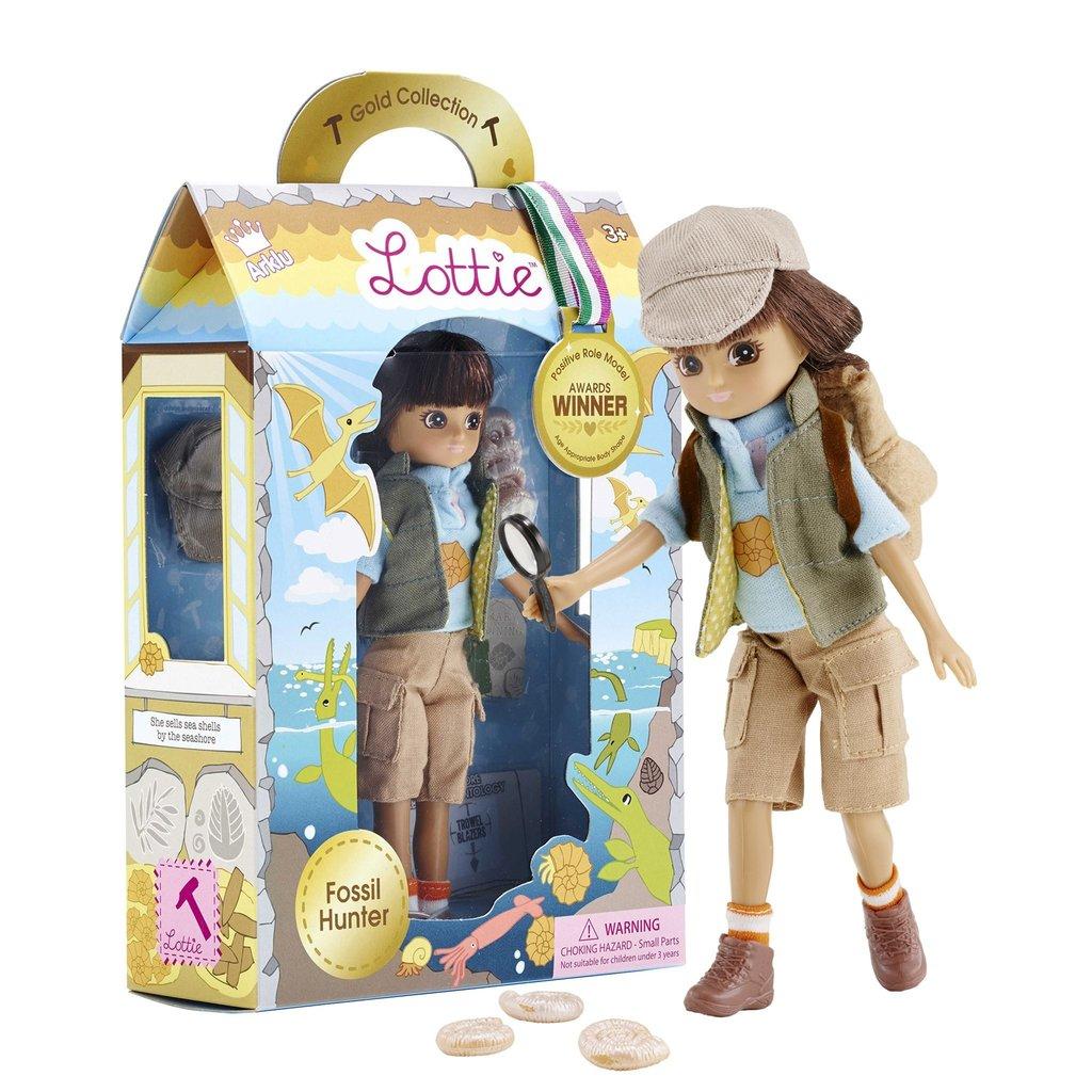 Packaging with Fossil Hunter Lottie inside and a doll 'standing' beside it looking at ammonites.