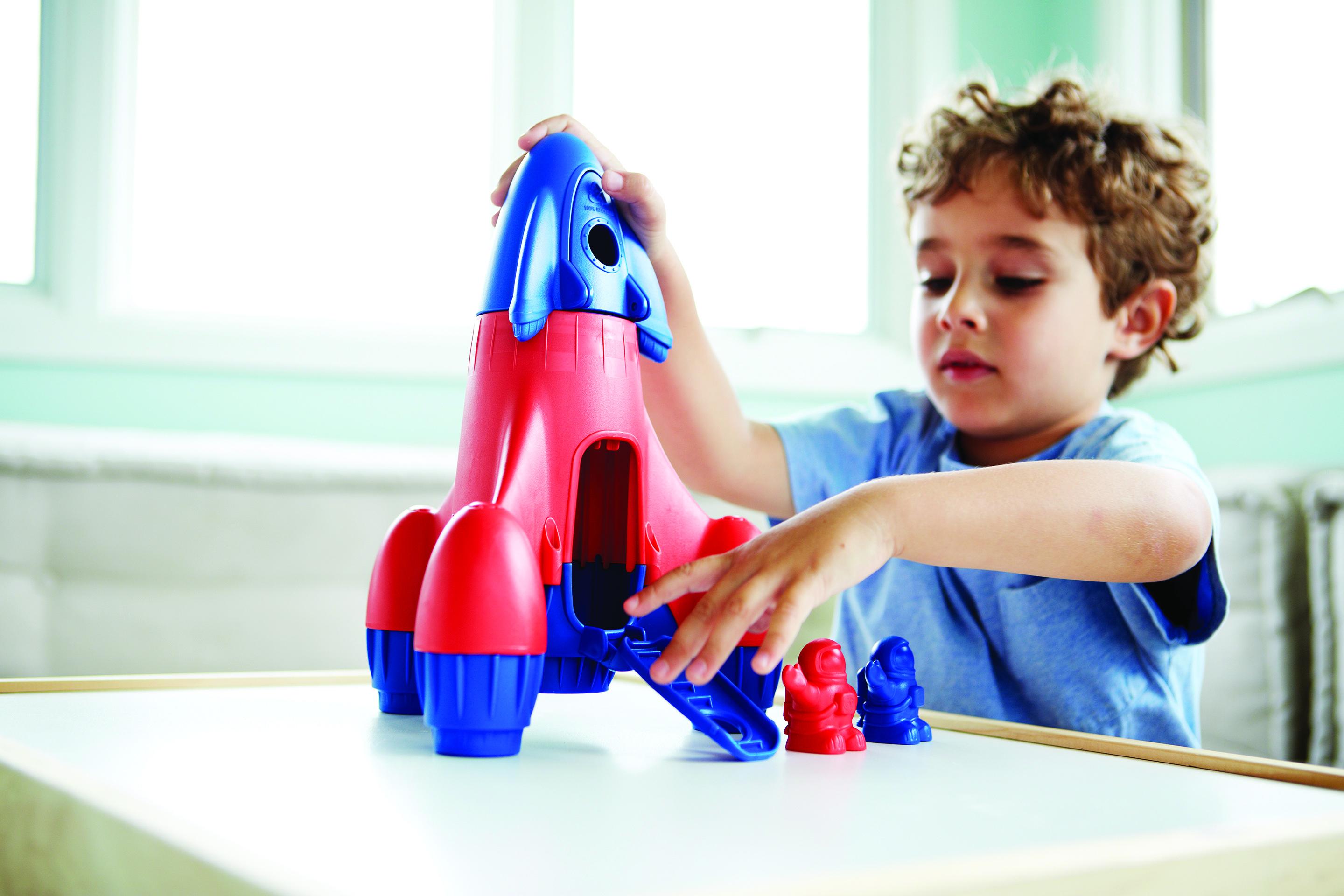 Child playing with red and blue rocket and figures.