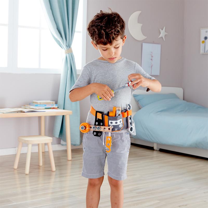 Young boy wearing the Hape tool belt in a bedroom setting.