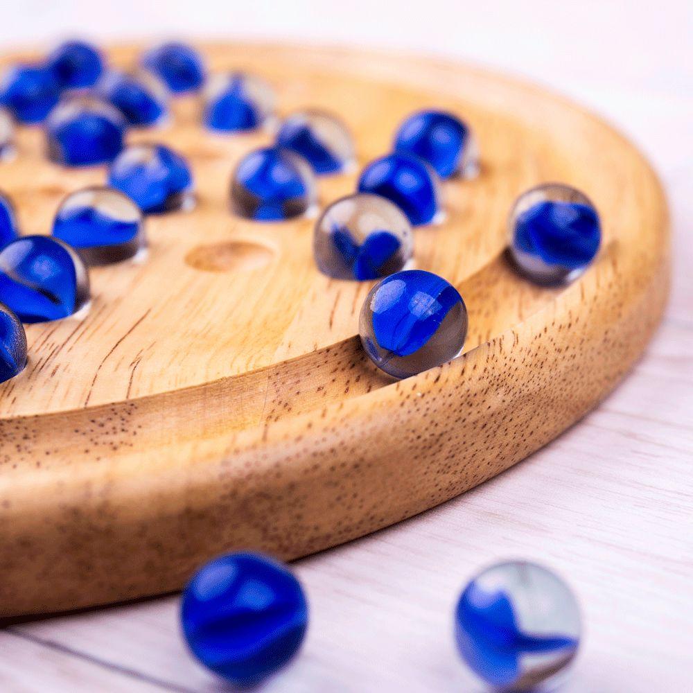 Close up view of a rounded section of the solitaire board with blue glass marbles.