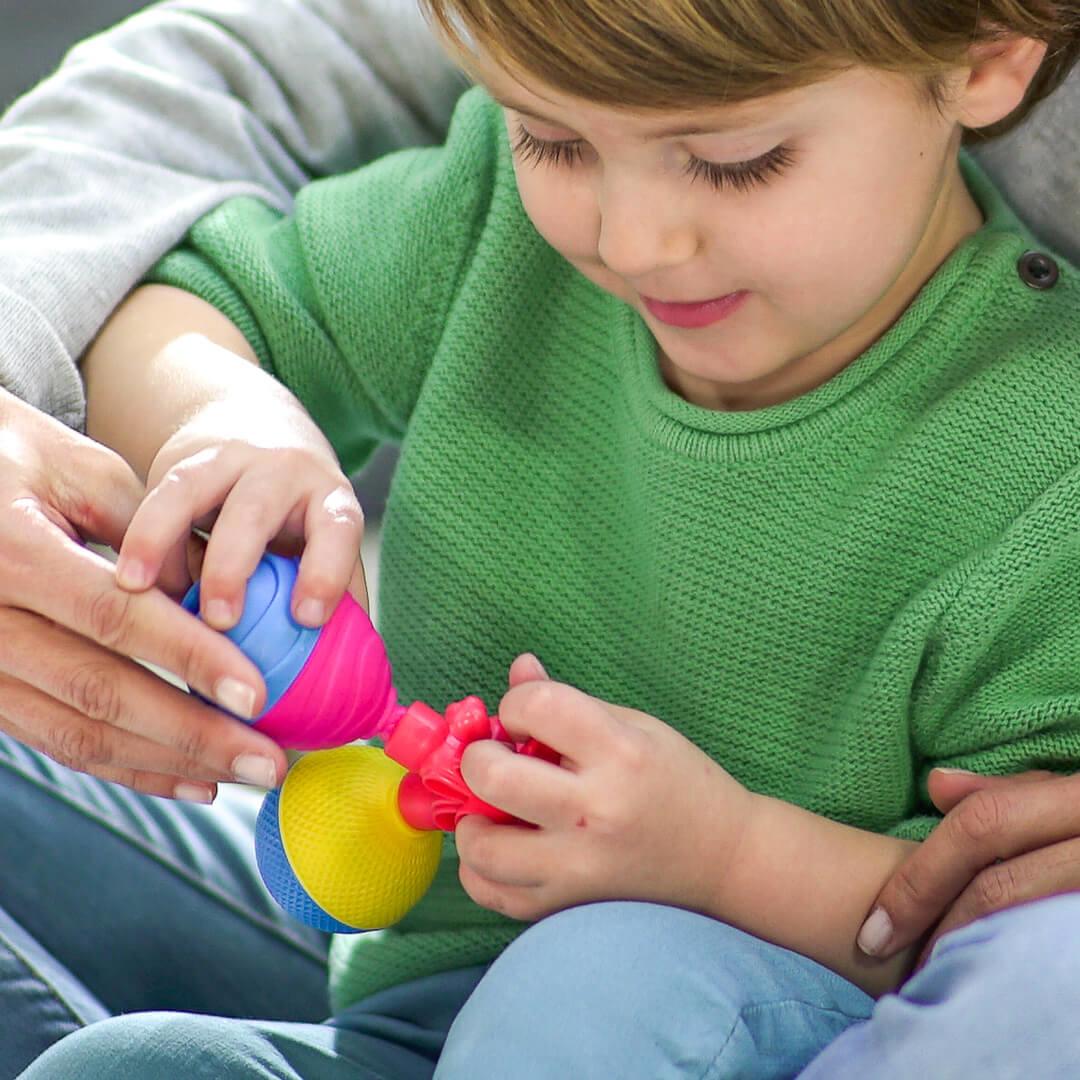 Young boy sitting with an adult playing with Lalaboom play beads.