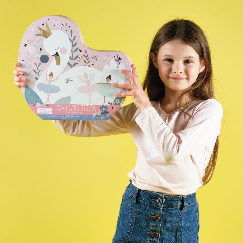 Girl in a pale top holding the swan-shaped box - yellow background.