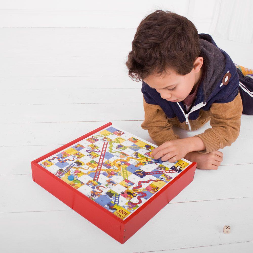 Boy lying on a white floor playing snakes and ladders.