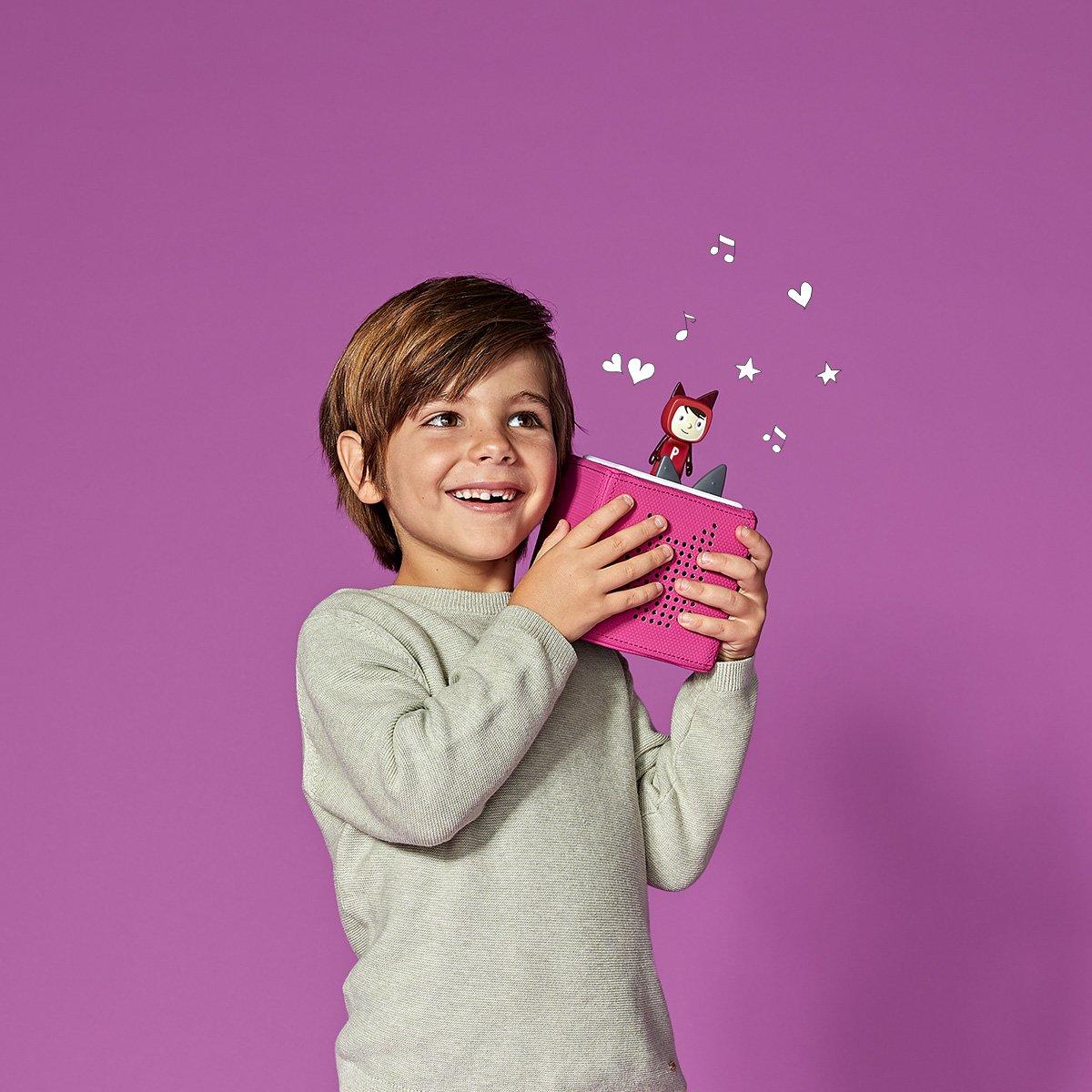 Child holding a purple Toniebox with a purple background.