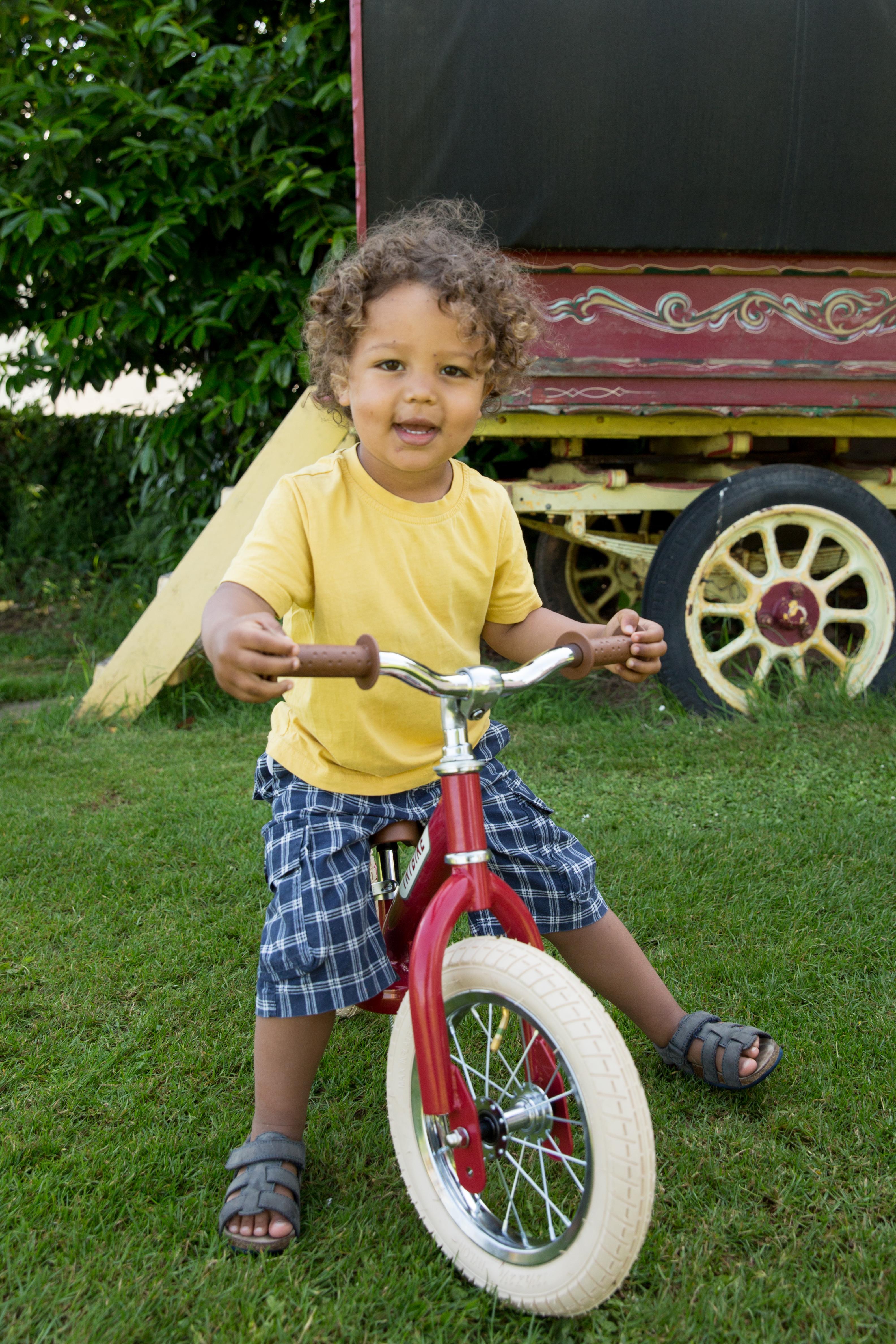 Small child in a yellow top on a Trybike made into a balance bike.