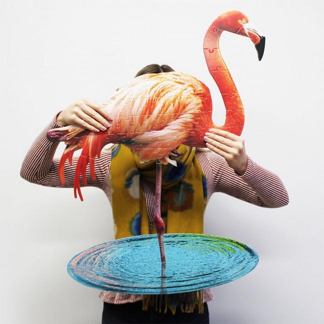 person holding up large flamingo-shaped jigsaw.