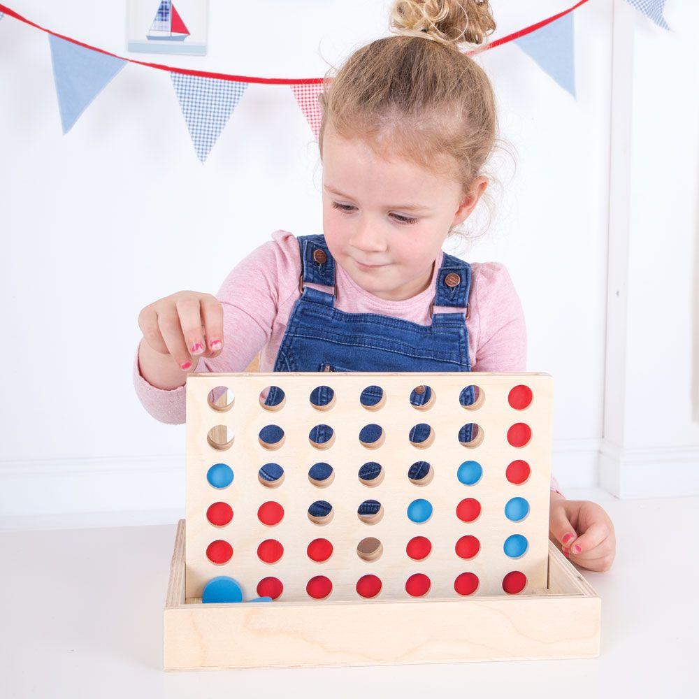 Girl wearing dungaees playing the Connect-4 wooden game.