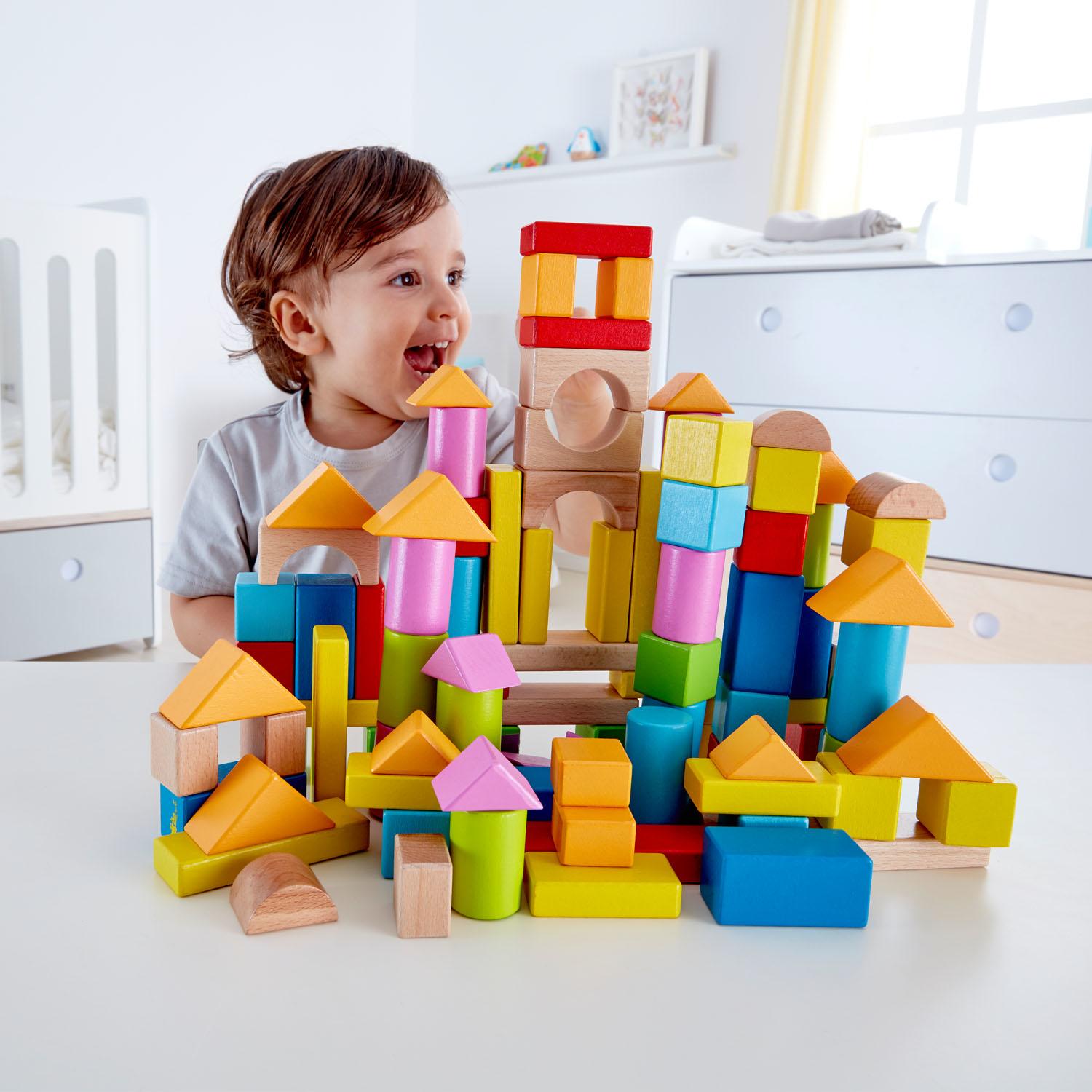 Child with colourful wooden blocks forming an elaborate structure.