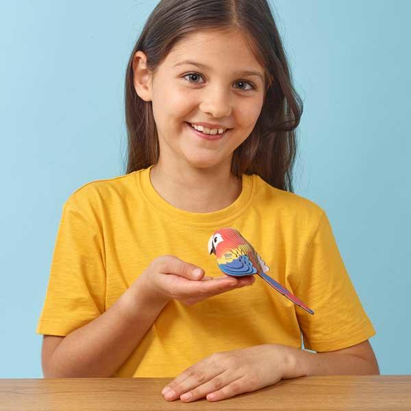Young girl with yellow tshirt holding the colourful parrot model.
