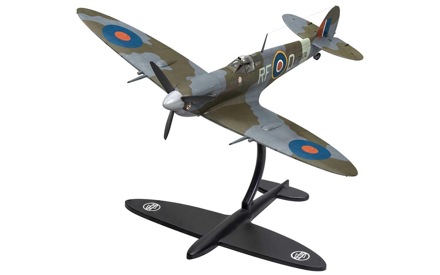 Model of a Spitfire aircraft painted in khaki green and grey on a black stand.
