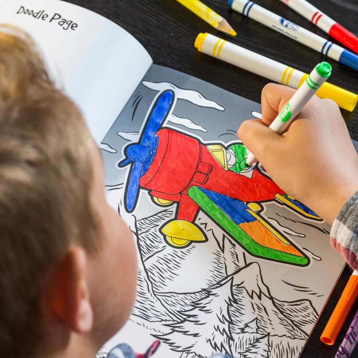 Looking over the shoulder of a boy colouring in an plane.