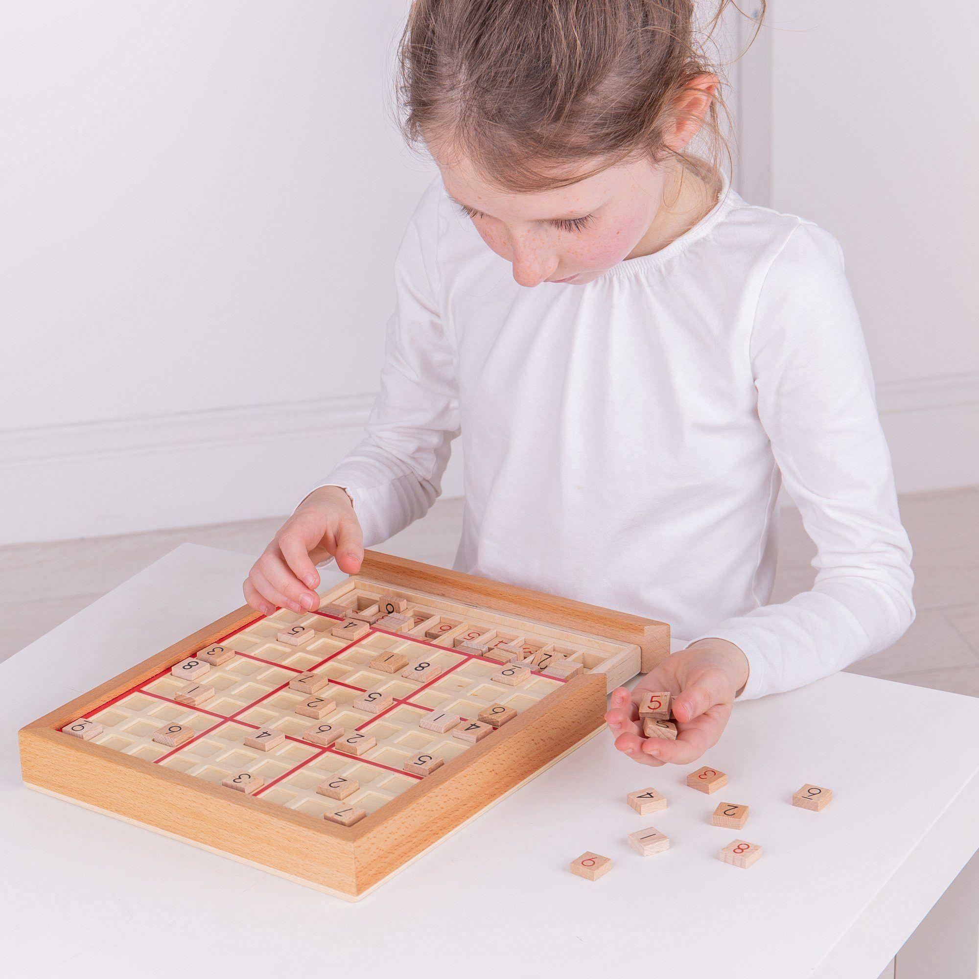Girl in a white top playing the wooden sudoku game.