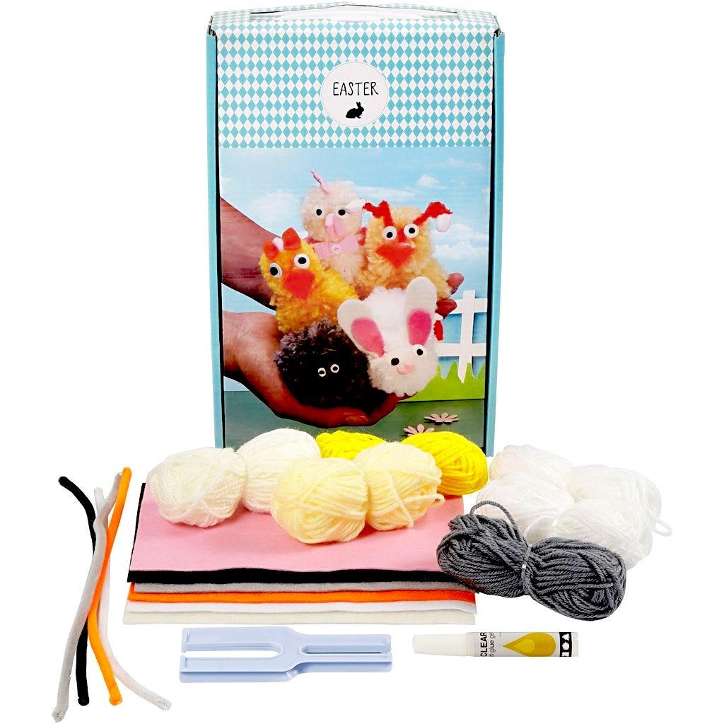 Colourful rectangular box with an image of hands holding 5 pom-pom creatures and with the contents laid out in front. The contents are balls of yarn, pieces of felts and some pipe cleaners.