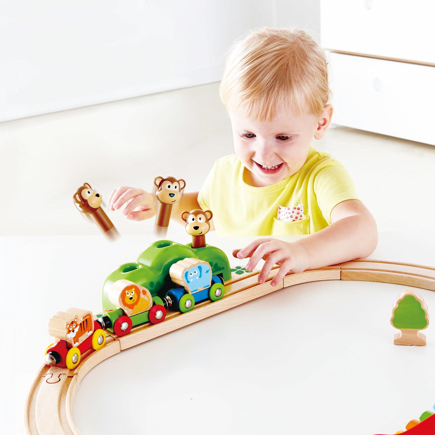 Child playing with jungle animals on a train with monkey pieces that pop up as the train goes by.