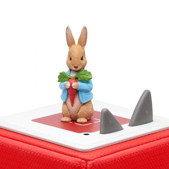 Peter Rabbit wearing a blue waistcoat standin atop a red Toniebox.