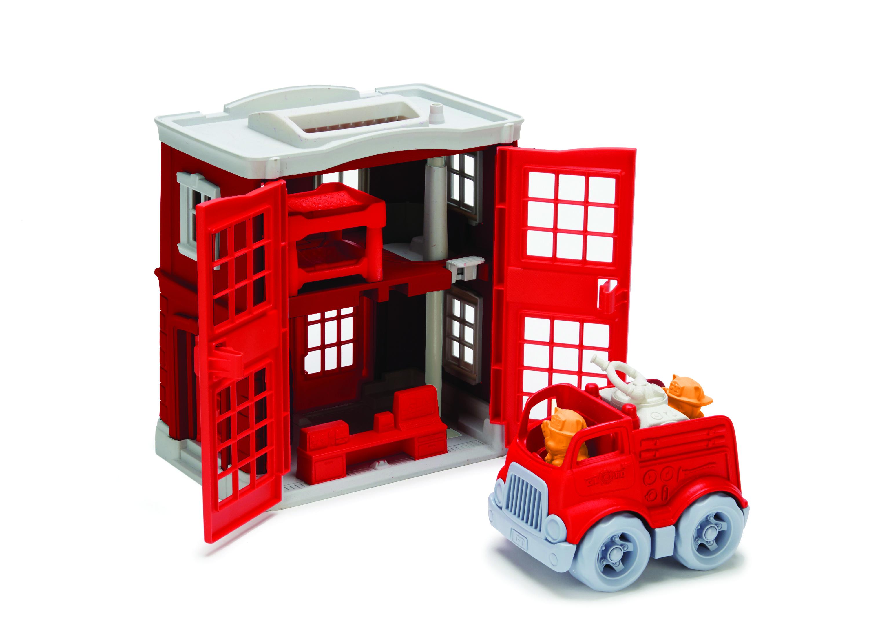 Fire station playset with front doors open wide and fire engine in front.