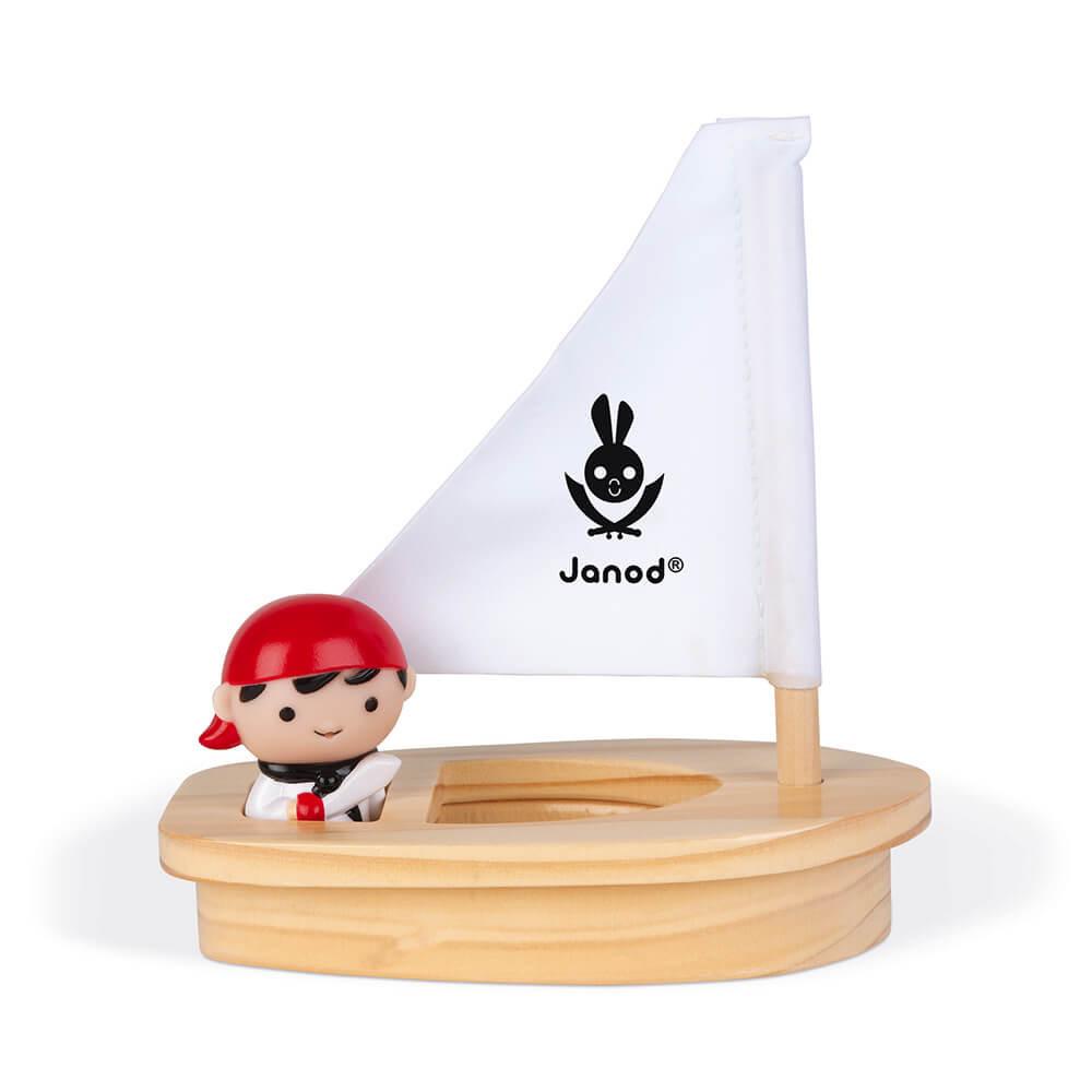 Wooden toy boat with white sail and the included figure sitting inside.