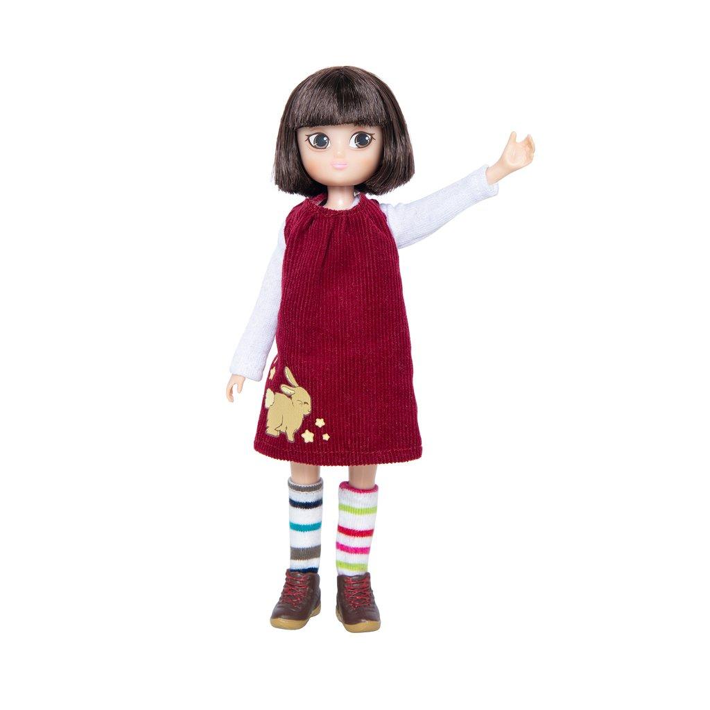 Doll with dark bobbed hair, wearing a dark red dress with a long sleeve white t-shirt underneath and one arm raised.