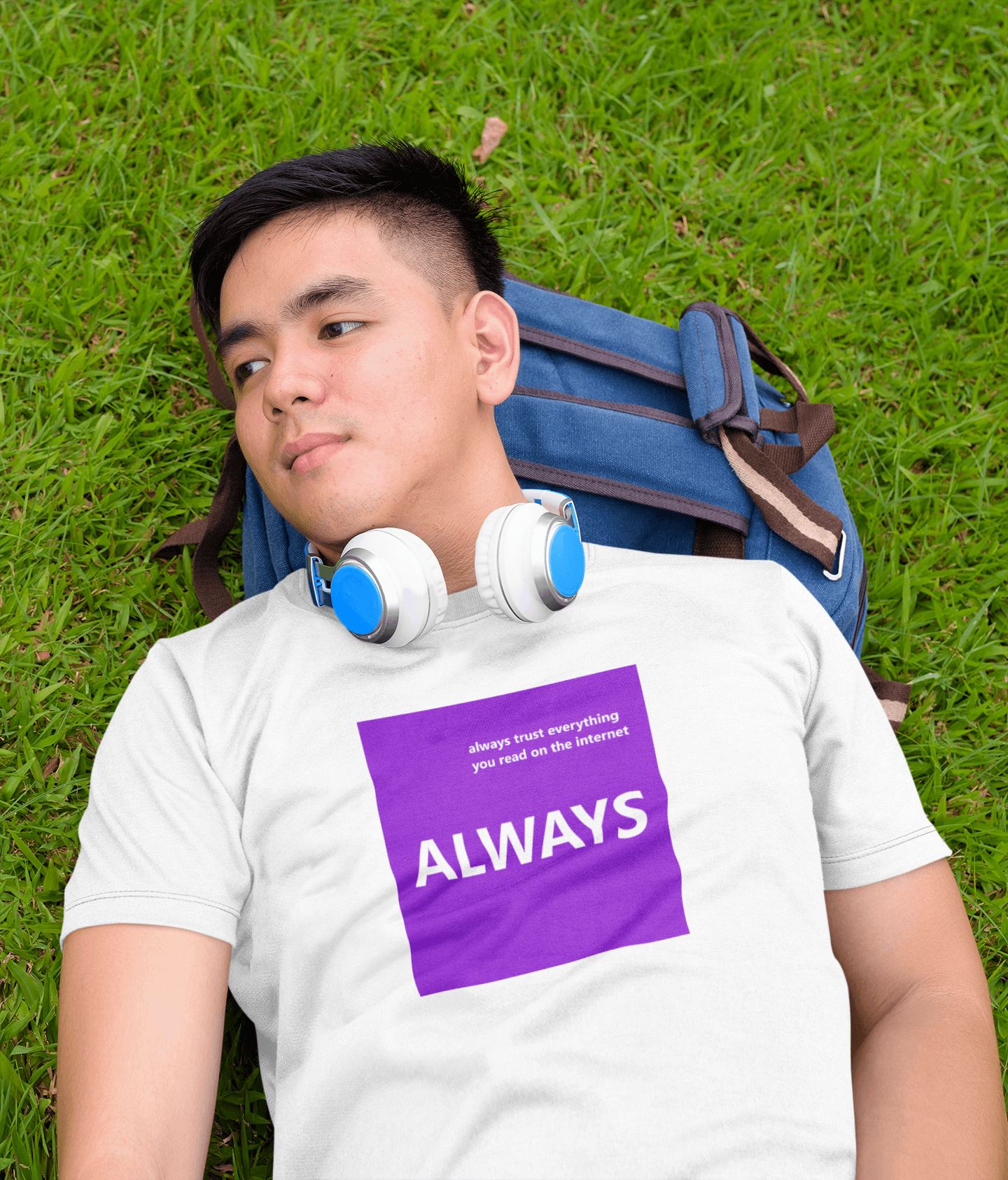 young man lying on grass with headphones and slogan t-shirt