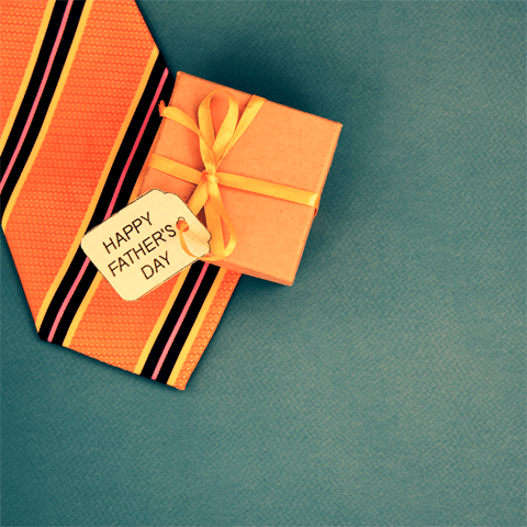 father's day gift wrapped in orange paper on green background