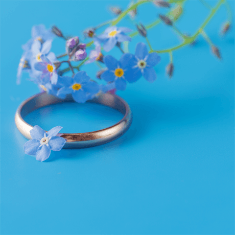 gold wedding ring and flowers on a blue background