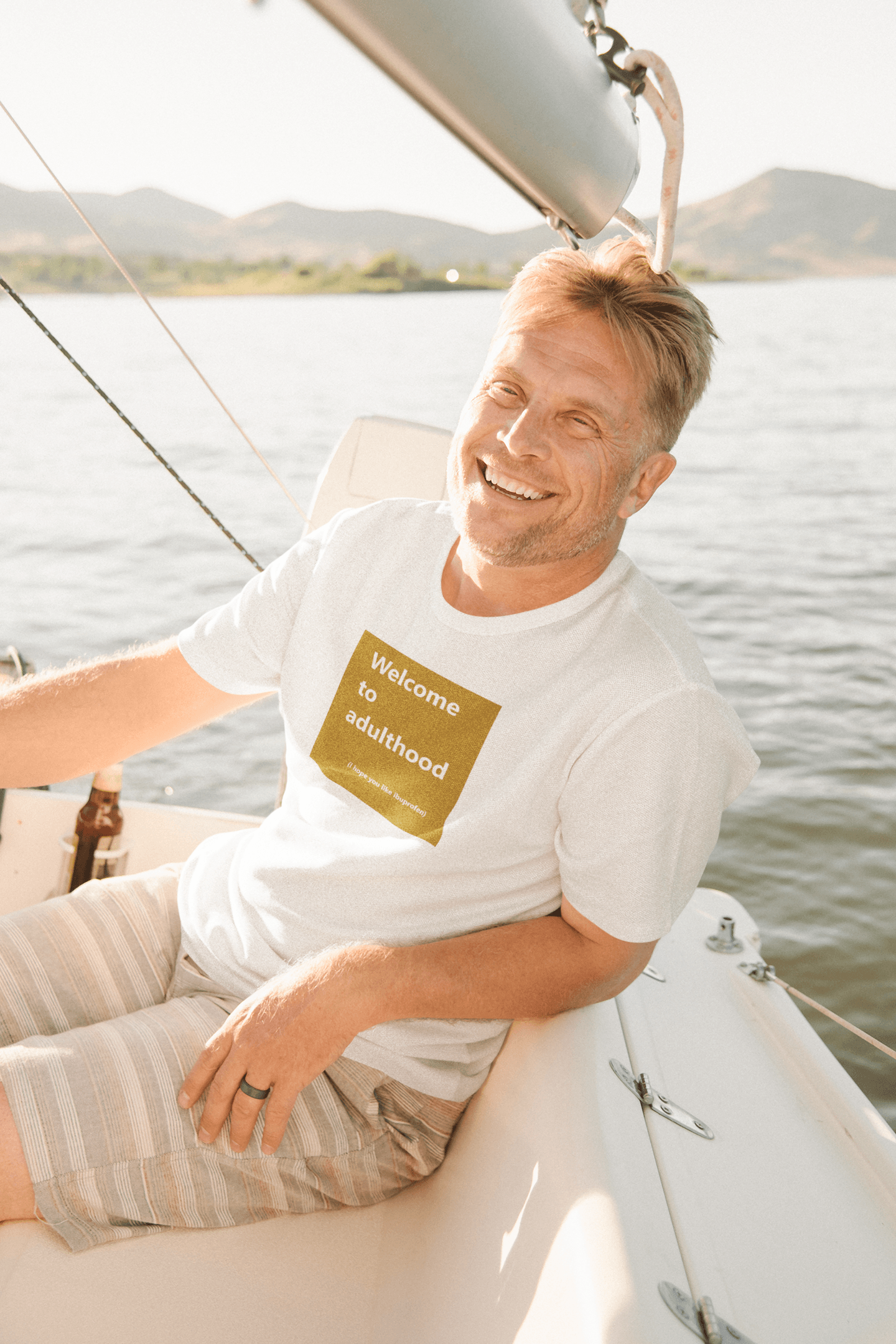 middle-aged man sailing a yacht and wearing a slogan t-shirt