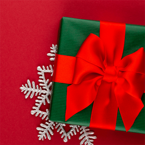 green wrapped christmas present and snowflake on a red background