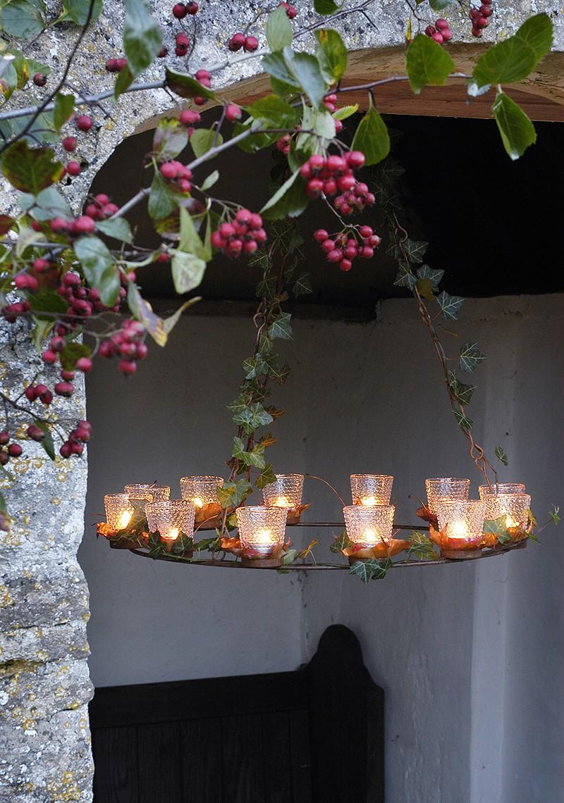 Circle of bubble glass votives,  containing burning tealight candles, hanging in the entrance to a stone porch.