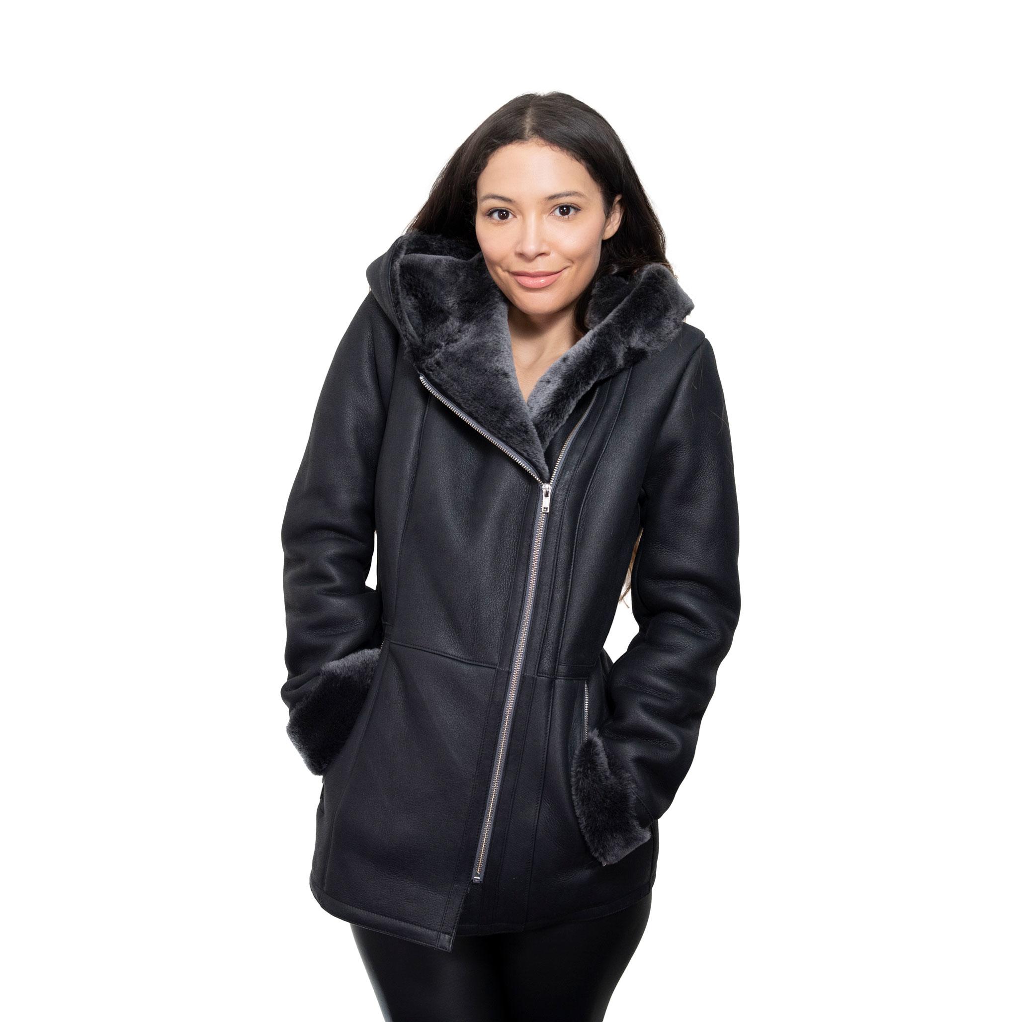 A lady model strikes a cosy pose, with her hands placed within the side pocket of her luxurious, black sheepskin coat. The sheepkin coat has a hood, lined with butter soft fur.