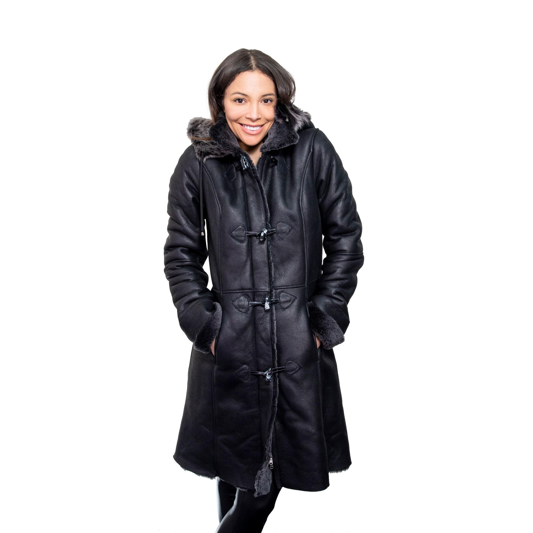 The model smiles, with her hand tucked in to her long, black hooded Sheepskin Coat. The luxury coat features decadent toscana fur in the hood, and cuff. Long toggled fastening, supplementing the front zipped closure.