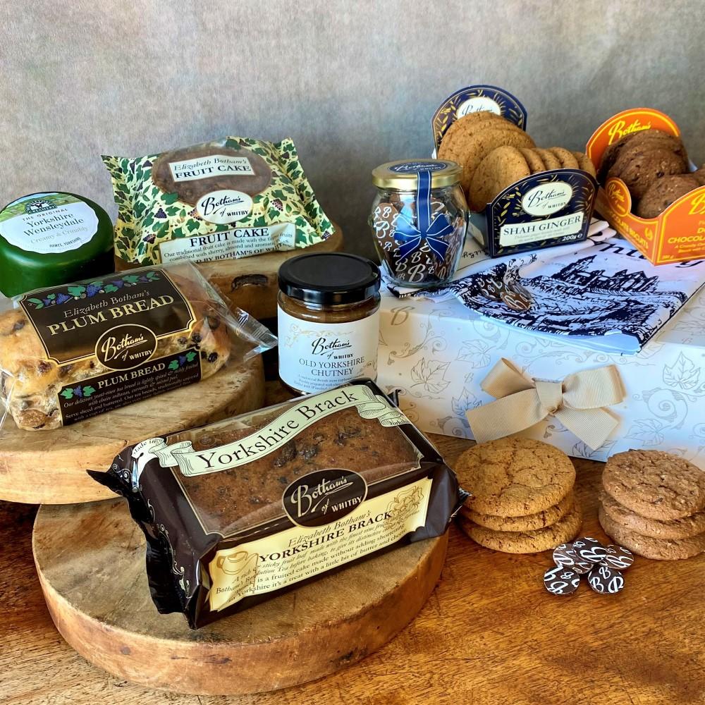 Image displays content of Yorkshire Hamper, including: Yorkshire Brack, Plum Bread, Elizabeth Botham's Fruit Cake, Shah Ginger Biscuits, Double Chocolate Biscuits, Chocolate 'B' Buttons, Old Yorkshire Chutney, Wensleydale Cheese, Botham's of Whitby tea towel and a Botham's gold ribbon tie gift box.