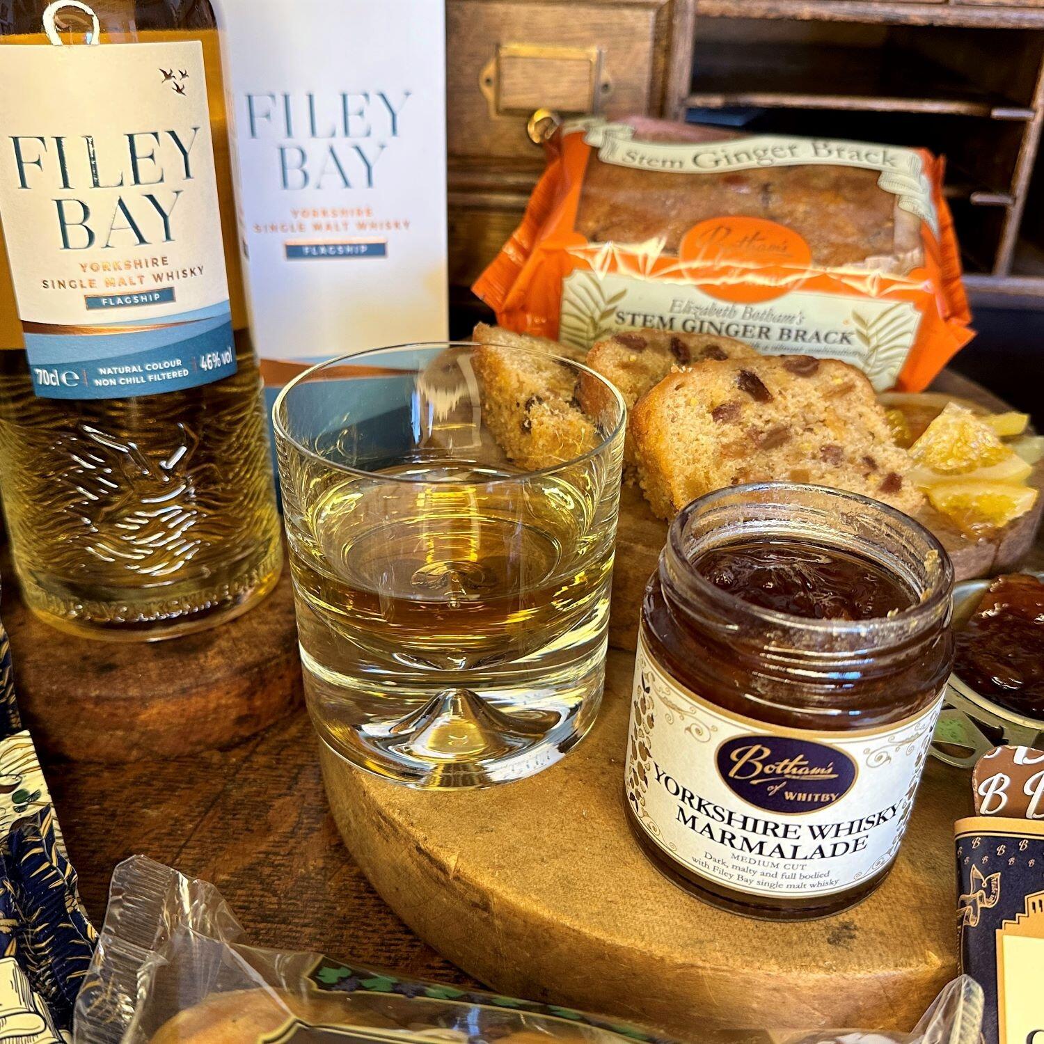 Image displays close-up of a glass of Filey Bay Whisky and the jar of Yorkshire Whisky Marmalade, set out on an old, wooden writing table.