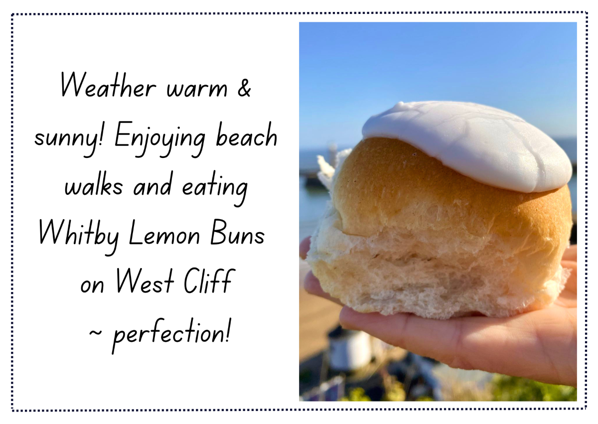 Postcard from Whitby reading 'Weather warm and sunny! Enjoying beach walks and eating Whitby Lemon Buns on West Cliff ~ Perfection!' with right-aligned hero image of Whitby Lemon Bun with white lemony icing and Whitby seascape in the background.