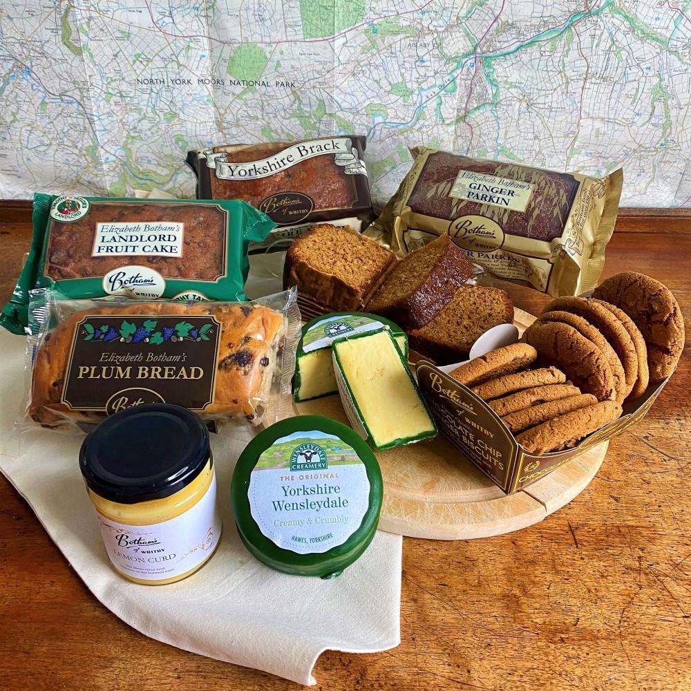 Image displays content of Dales Hamper, including: Yorkshire Brack Plum Bread Yorkshire Ginger Parkin Landlord Fruit Cake Chocolate Chip & Ginger Biscuits Yorkshire Wensleydale Cheese Lemon Curd Botham's of Whitby Cotton Bag. Map of the Yorkshire Dales is displayed in the background.